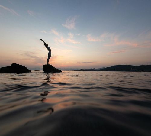 Silhouette of a person in a yoga pose against a beautiful sunset.
